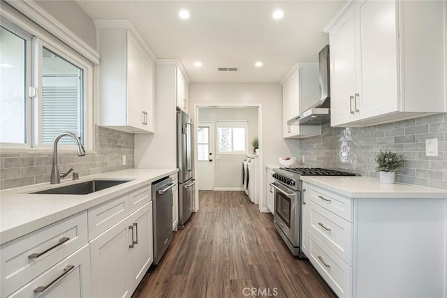 341 Cumberland Rd, Glendale, CA 91202 - kitchen with stainless steel appliances, wall chimney range hood, washing machine and dryer, white cabinetry, and dark wood-style flooring