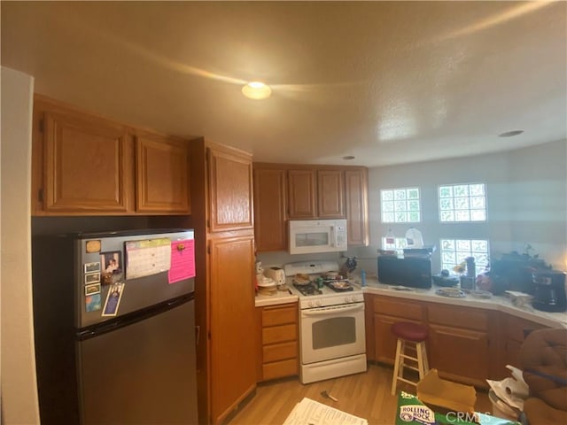 1853 Corte Pulsera, Oceanside, CA 92056 - kitchen featuring white appliances, light wood-style flooring, light countertops, and brown cabinets