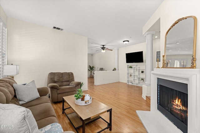 489 W Summerfield Cir, Anaheim, CA 92802 - living area featuring light wood-type flooring, a ceiling fan, a lit fireplace, decorative columns, and built in shelves