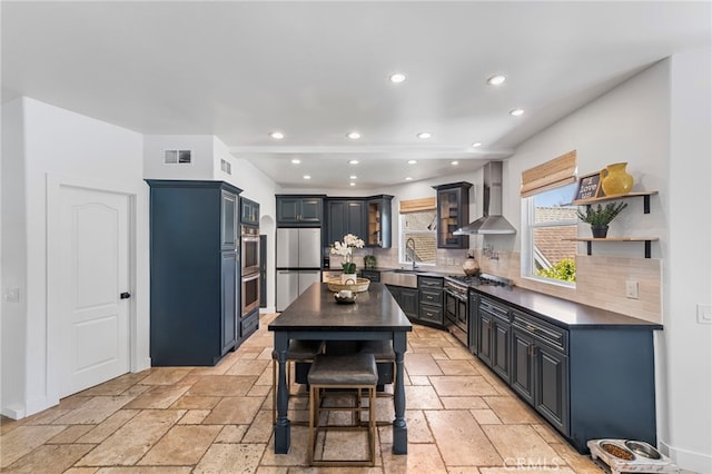 31675 Via Pato, Coto De Caza, CA 92679 - kitchen with appliances with stainless steel finishes, wall chimney exhaust hood, dark countertops, stone tile flooring, and recessed lighting