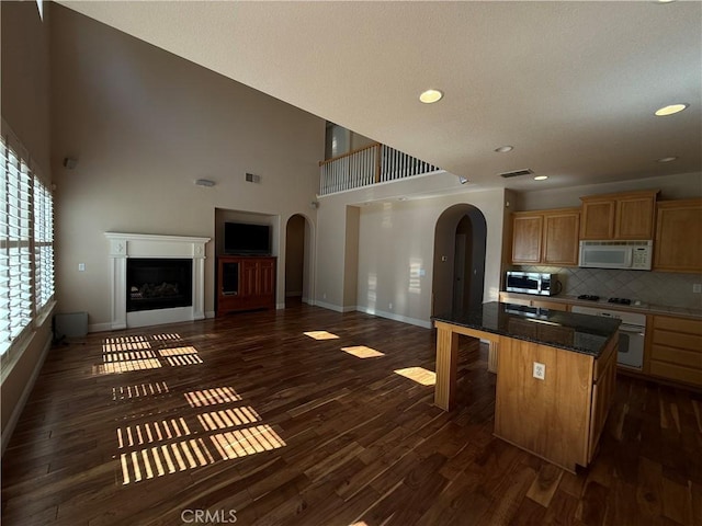 4125 Sattui Ct, Merced, CA 95348 - kitchen with white appliances, arched walkways, open floor plan, a high ceiling, and dark wood-type flooring
