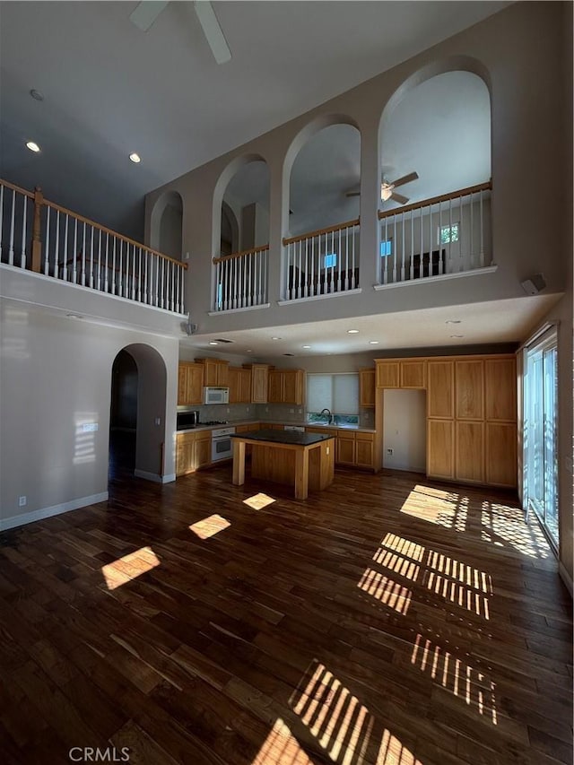 4125 Sattui Ct, Merced, CA 95348 - unfurnished living room featuring a ceiling fan, a high ceiling, dark wood-style floors, arched walkways, and recessed lighting