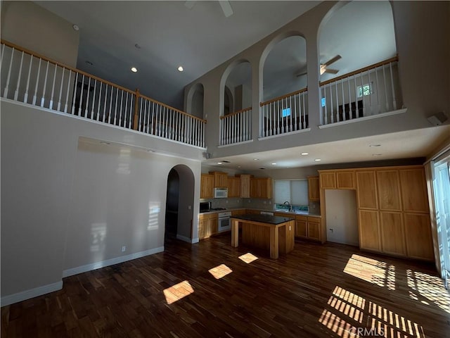 4125 Sattui Ct, Merced, CA 95348 - kitchen with a ceiling fan, stove, white microwave, a center island, and a high ceiling