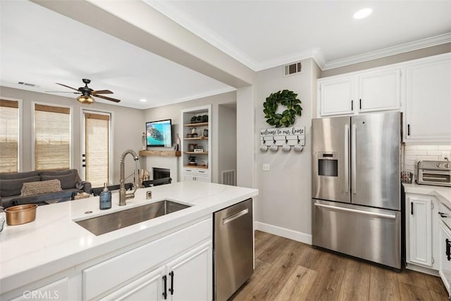 42 Livingston Pl, Ladera Ranch, CA 92694 - kitchen with stainless steel appliances, open floor plan, wood finished floors, ornamental molding, and white cabinets