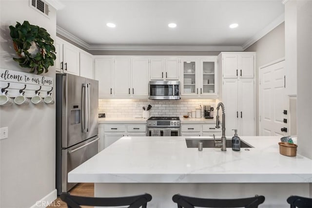 42 Livingston Pl, Ladera Ranch, CA 92694 - kitchen with stainless steel appliances, a breakfast bar, white cabinetry, ornamental molding, and recessed lighting