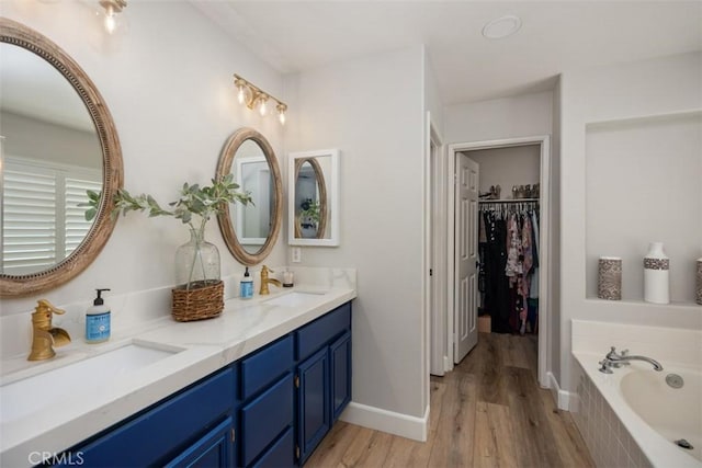 42 Livingston Pl, Ladera Ranch, CA 92694 - bathroom with double vanity, a bath, wood finished floors, and a walk in closet