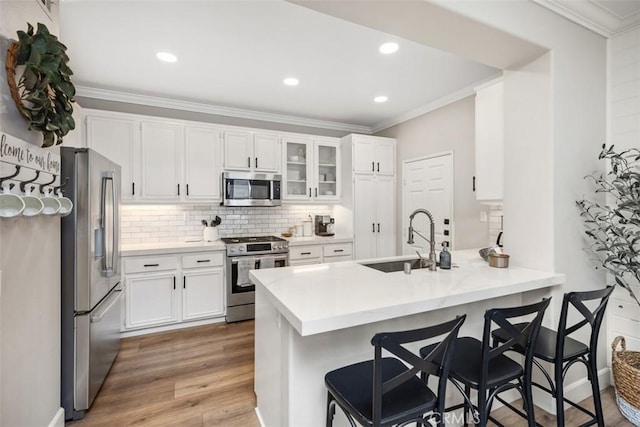 42 Livingston Pl, Ladera Ranch, CA 92694 - kitchen with stainless steel appliances, a peninsula, ornamental molding, tasteful backsplash, and white cabinetry