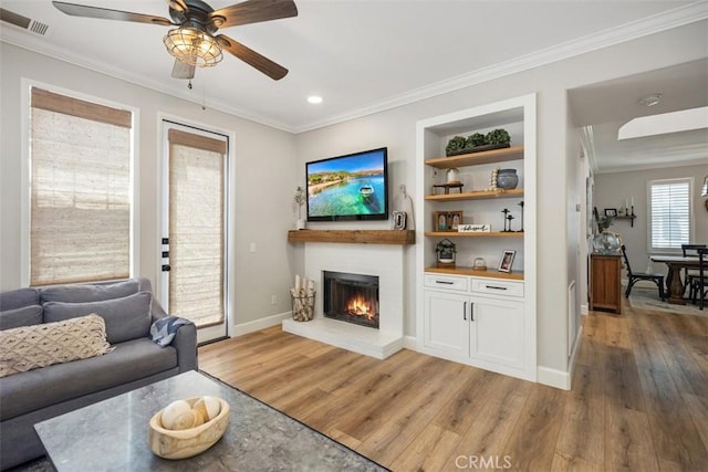 42 Livingston Pl, Ladera Ranch, CA 92694 - living area with light wood-style flooring, crown molding, a lit fireplace, ceiling fan, and built in shelves