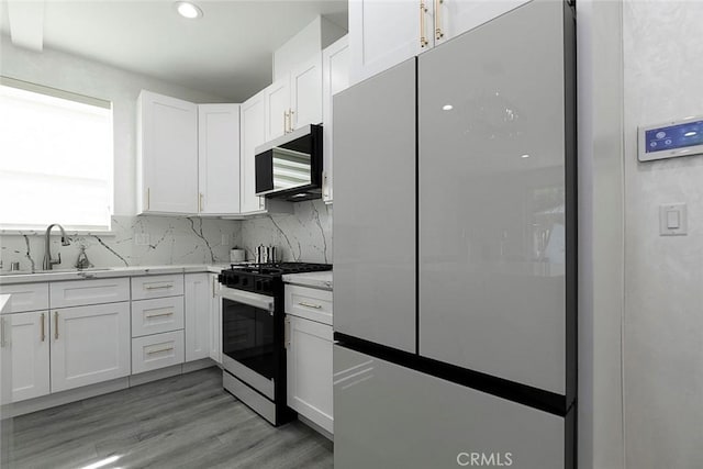 9124 N Nilo Ln, Panorama City, CA 91402 - kitchen featuring freestanding refrigerator, gas range oven, white cabinetry, tasteful backsplash, and recessed lighting