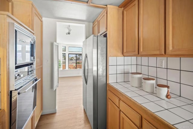 3531 Columbia St, San Diego, CA 92103 - kitchen featuring tile counters, appliances with stainless steel finishes, backsplash, and light wood finished floors