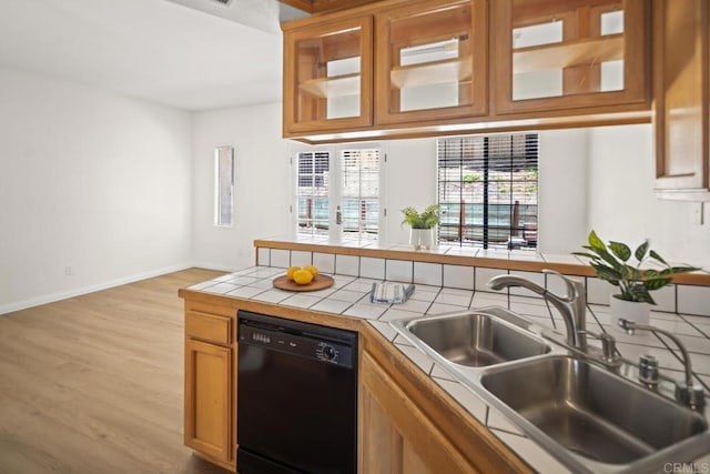 3531 Columbia St, San Diego, CA 92103 - kitchen with black dishwasher, tile counters, light wood-type flooring, glass insert cabinets, and brown cabinetry