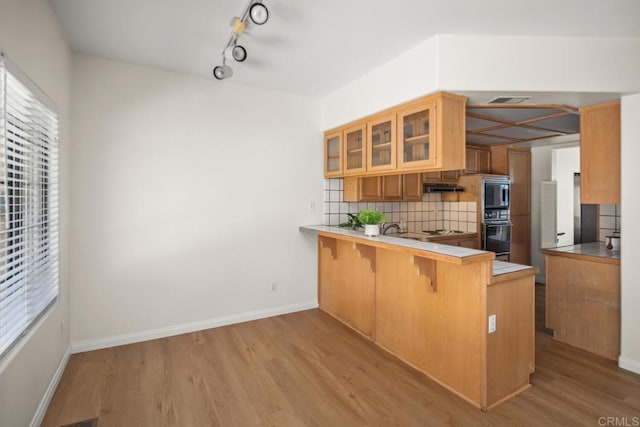 3531 Columbia St, San Diego, CA 92103 - kitchen with light wood finished floors, backsplash, glass insert cabinets, a peninsula, and plenty of natural light