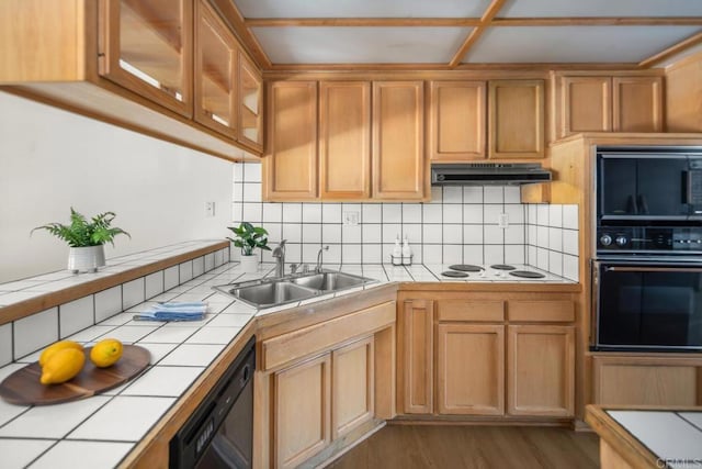 3531 Columbia St, San Diego, CA 92103 - kitchen featuring tile counters, black appliances, under cabinet range hood, wood finished floors, and decorative backsplash