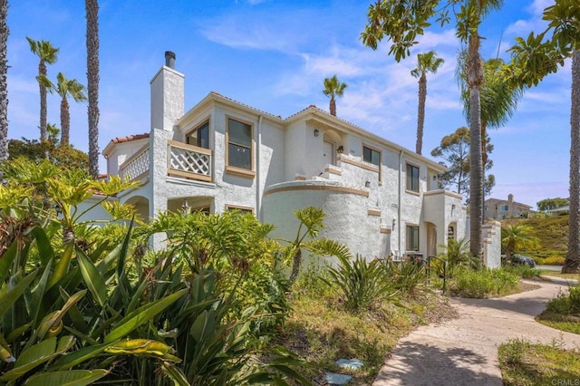 13292 Salmon River Rd Unit 204, San Diego, CA 92129 - view of property exterior featuring a balcony, a chimney, stucco siding, and a tiled roof