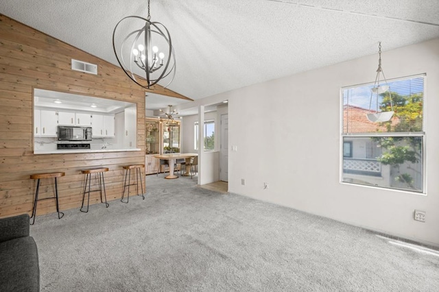 13292 Salmon River Rd Unit 204, San Diego, CA 92129 - living area with a chandelier, lofted ceiling, wooden walls, light carpet, and a textured ceiling