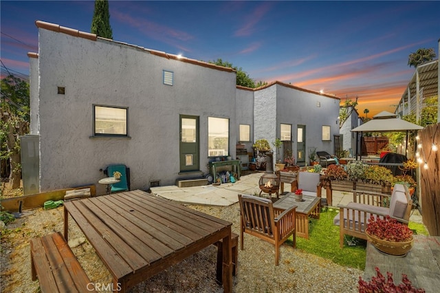 1928 Rosalia Rd, Los Angeles, CA 90027 - back of house at dusk with a patio, stucco siding, a gazebo, an outdoor living space, and outdoor dining space
