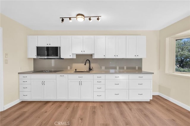 3777 N Arrowhead Ave, San Bernardino, CA 92405 - kitchen featuring stainless steel microwave, black electric cooktop, light wood-type flooring, and white cabinets
