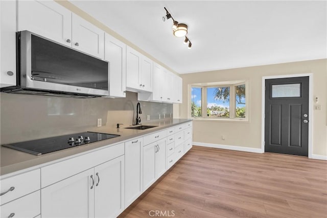 3777 N Arrowhead Ave, San Bernardino, CA 92405 - kitchen with stainless steel microwave, black electric cooktop, light wood-style floors, white cabinetry, and light countertops