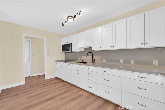 3777 N Arrowhead Ave, San Bernardino, CA 92405 - kitchen featuring stainless steel microwave, black electric cooktop, light wood-style flooring, white cabinets, and light countertops