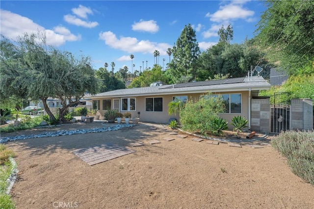 3777 N Arrowhead Ave, San Bernardino, CA 92405 - rear view of house with stucco siding, solar panels, and a patio area
