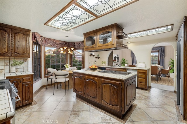 23511 Mirage Ln, Diamond Bar, CA 91765 - kitchen featuring tile countertops, arched walkways, a chandelier, and a skylight