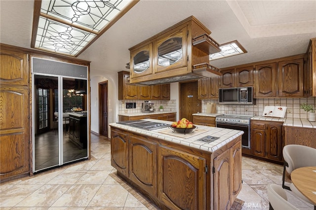 23511 Mirage Ln, Diamond Bar, CA 91765 - kitchen with stainless steel appliances, tile counters, a kitchen island, tasteful backsplash, and brown cabinetry