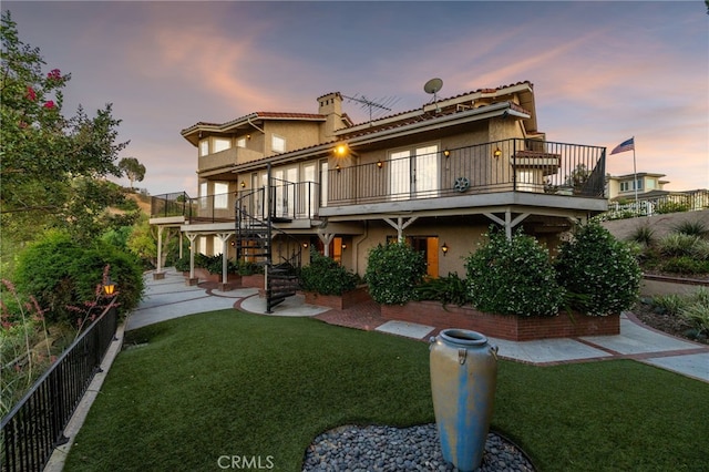 23511 Mirage Ln, Diamond Bar, CA 91765 - back of house at dusk with stairs, stucco siding, a chimney, and a balcony