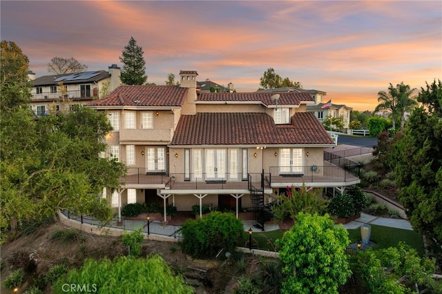 23511 Mirage Ln, Diamond Bar, CA 91765 - back of house at dusk with a tile roof, stucco siding, a chimney, french doors, and a patio area