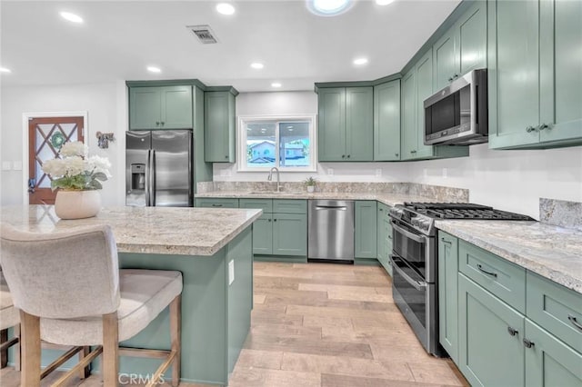 6721 E Coralite St, Long Beach, CA 90808 - kitchen with appliances with stainless steel finishes, green cabinetry, a breakfast bar, light countertops, and recessed lighting