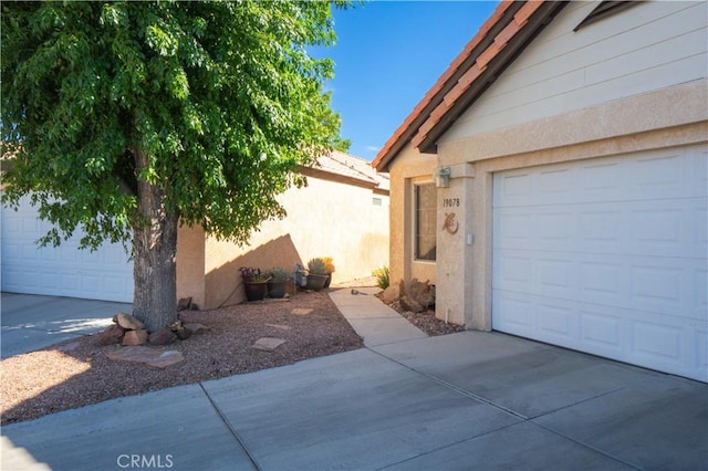 19078 Stoddard Way, Apple Valley, CA 92308 - view of side of property with a garage, stucco siding, and driveway