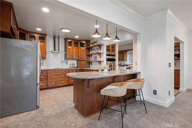 790 Manzanita St, Lakeport, CA 95453 - kitchen featuring freestanding refrigerator, wall chimney exhaust hood, crown molding, brown cabinetry, and a kitchen breakfast bar