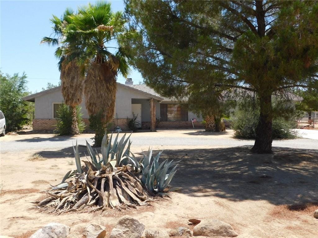 20049 Serrano Rd, Apple Valley, CA 92307 - view of property hidden behind natural elements featuring stucco siding, brick siding, and a fire pit