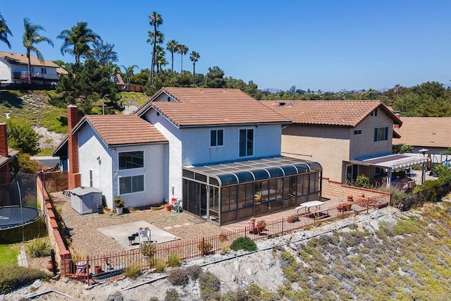 10323 Pine Grove St, Spring Valley, CA 91978 - back of house with a sunroom, a trampoline, a patio, a fenced backyard, and stucco siding