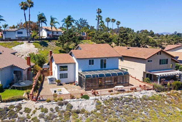 10323 Pine Grove St, Spring Valley, CA 91978 - rear view of property featuring a trampoline, a fenced backyard, a patio, a residential view, and a sunroom