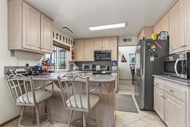 10323 Pine Grove St, Spring Valley, CA 91978 - kitchen featuring stainless steel appliances, a peninsula, light brown cabinetry, tasteful backsplash, and a breakfast bar area
