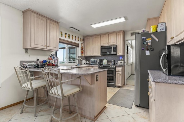 10323 Pine Grove St, Spring Valley, CA 91978 - kitchen featuring appliances with stainless steel finishes, a peninsula, light brown cabinetry, a breakfast bar area, and light tile patterned floors