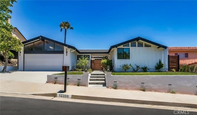 12350 Mclennan Ave, Granada Hills, CA 91344 - mid-century home featuring board and batten siding, concrete driveway, and an attached garage