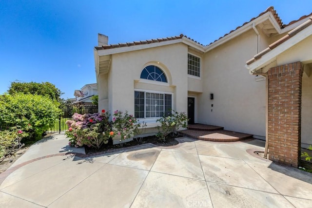 4330 E Cornwall Ave, Orange, CA 92867 - view of exterior entry featuring stucco siding, a chimney, a tiled roof, and a patio