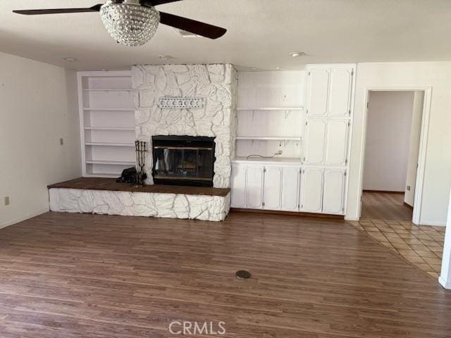 15163 Tournament Dr, Helendale, CA 92342 - unfurnished living room featuring ceiling fan, a fireplace, wood finished floors, and built in shelves