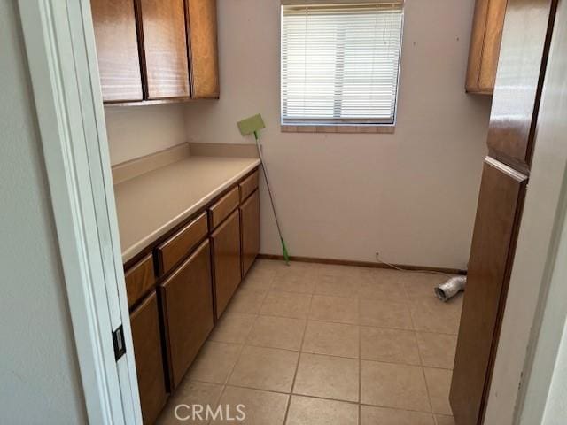 15163 Tournament Dr, Helendale, CA 92342 - kitchen featuring light countertops, light tile patterned floors, and brown cabinets