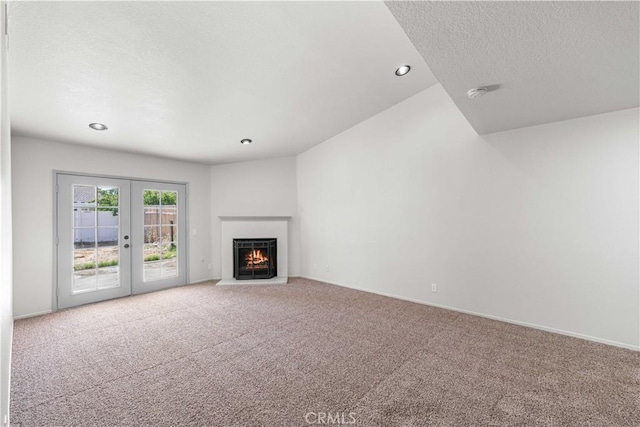 37632 15th St E, Palmdale, CA 93550 - unfurnished living room with carpet flooring, a textured ceiling, french doors, a lit fireplace, and recessed lighting
