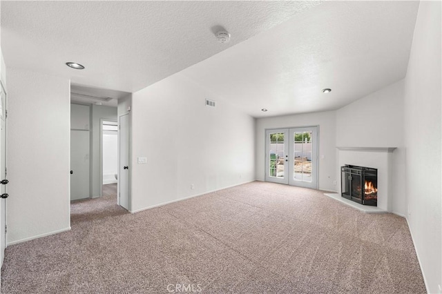 37632 15th St E, Palmdale, CA 93550 - unfurnished living room with carpet floors, french doors, a warm lit fireplace, and a textured ceiling