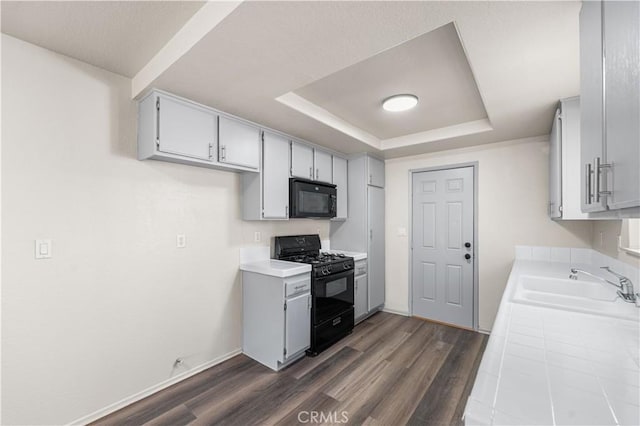 37632 15th St E, Palmdale, CA 93550 - kitchen with black appliances, dark wood finished floors, a tray ceiling, and tile counters