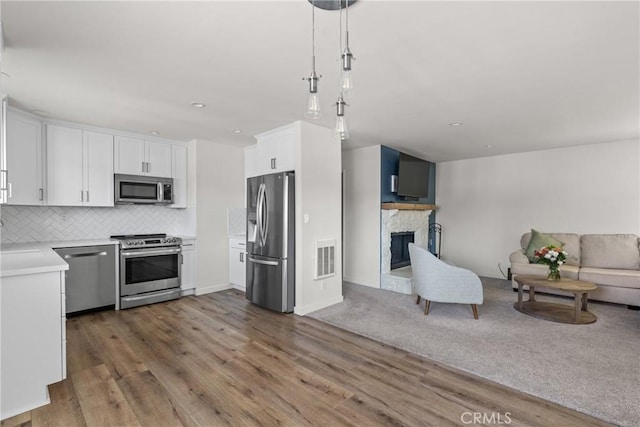 242 N 10th St Unit 242, Grover Beach, CA 93433 - kitchen featuring appliances with stainless steel finishes, open floor plan, white cabinets, wood finished floors, and tasteful backsplash