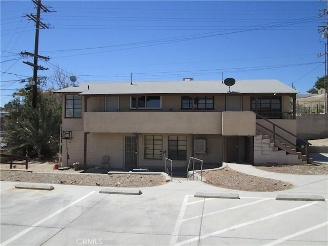 201 W Williams St, Barstow, CA 92311 - view of front facade featuring stucco siding, uncovered parking, and stairs