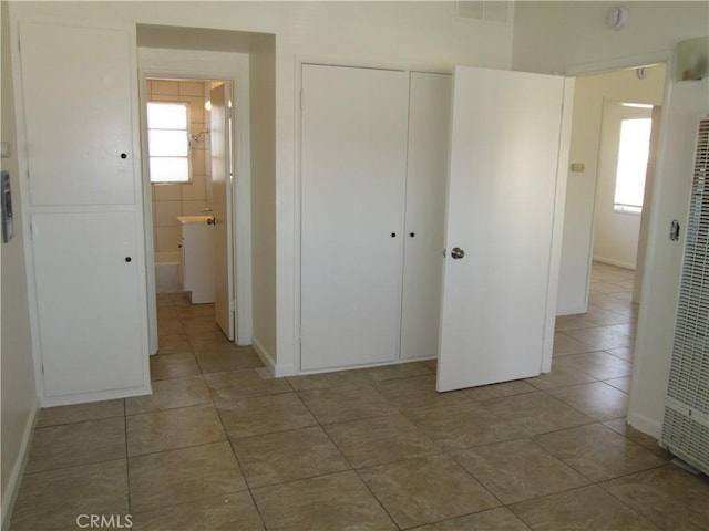 201 W Williams St, Barstow, CA 92311 - unfurnished bedroom featuring tile patterned flooring, a closet, multiple windows, and a heating unit