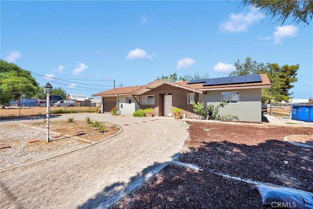 10000 8th Ave, Hesperia, CA 92345 - ranch-style house with a garage, solar panels, driveway, and stucco siding