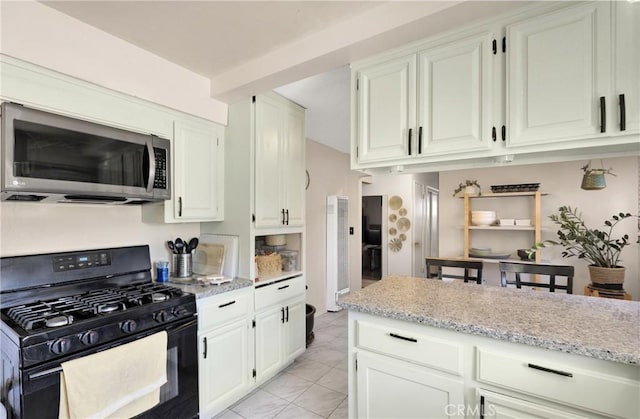 10000 8th Ave, Hesperia, CA 92345 - kitchen featuring stainless steel microwave, gas stove, white cabinetry, and light stone counters