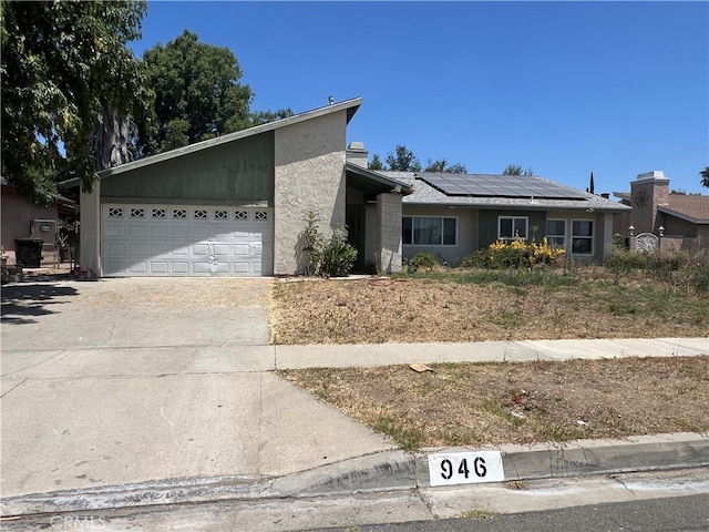 946 W Woodcrest, Bloomington, CA 92316 - view of front of property with concrete driveway, roof mounted solar panels, a garage, and stucco siding