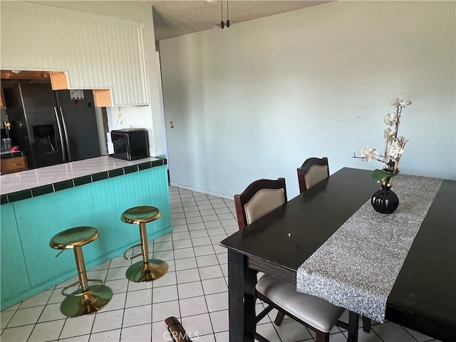 946 W Woodcrest, Bloomington, CA 92316 - kitchen with black fridge with ice dispenser, tile counters, light tile patterned floors, and a breakfast bar